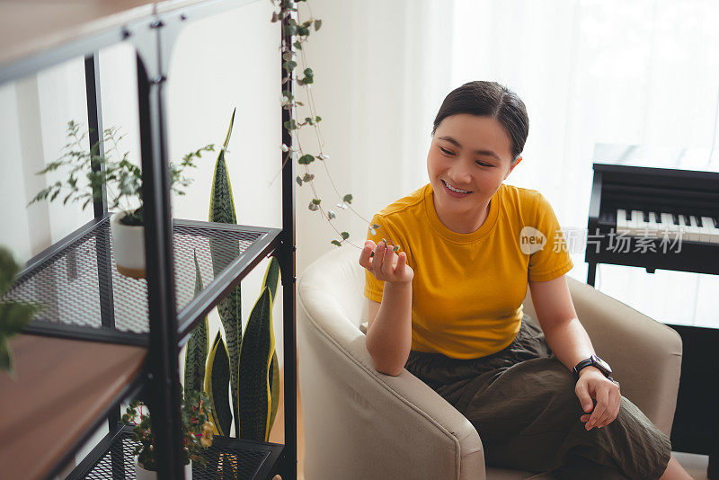 亚洲女性坐在家里客厅的扶手椅上享受放松时光。