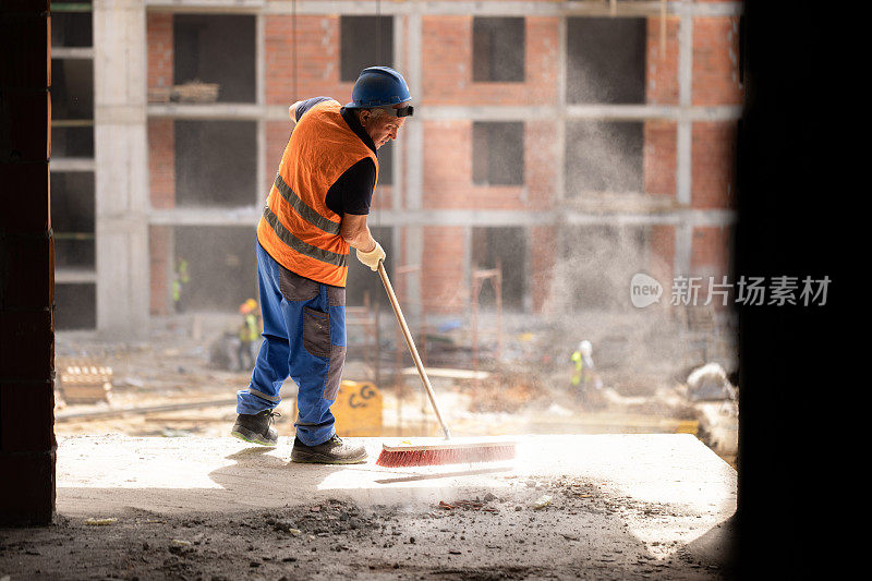 建筑工人用扫帚清理工地上的灰尘