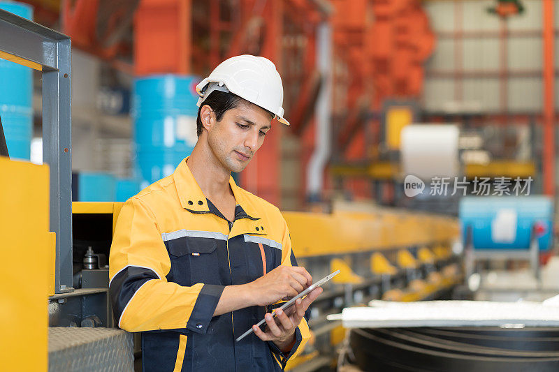 男性工厂工人在工厂的生产线上使用数字平板电脑检查生产质量。男性工程师在工厂用平板电脑检查机器零件