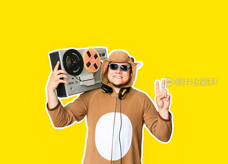 一个人穿着奶牛的角色扮演服装，带着黄色背景的磁带录音机。穿动物睡衣的人。派对创意的搞笑照片。迪斯科复古音乐。