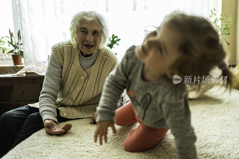 曾祖母在家里和蹒跚学步的孩子玩耍。