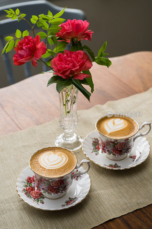 花瓶中的红玫瑰与一对20世纪60年代复古骨瓷杯中的平白咖啡