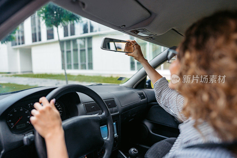 年轻女子在车里调整后视镜