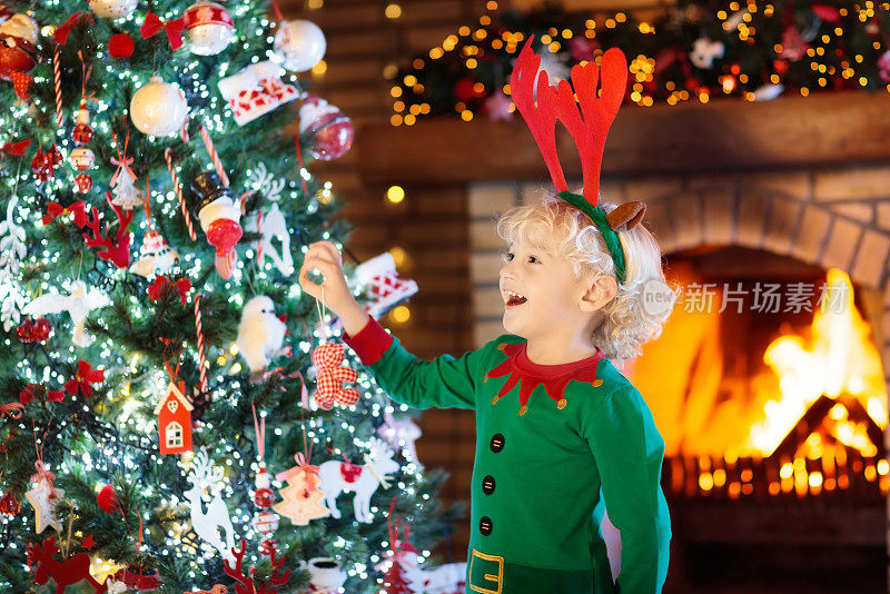 圣诞夜，孩子站在圣诞树和壁炉旁