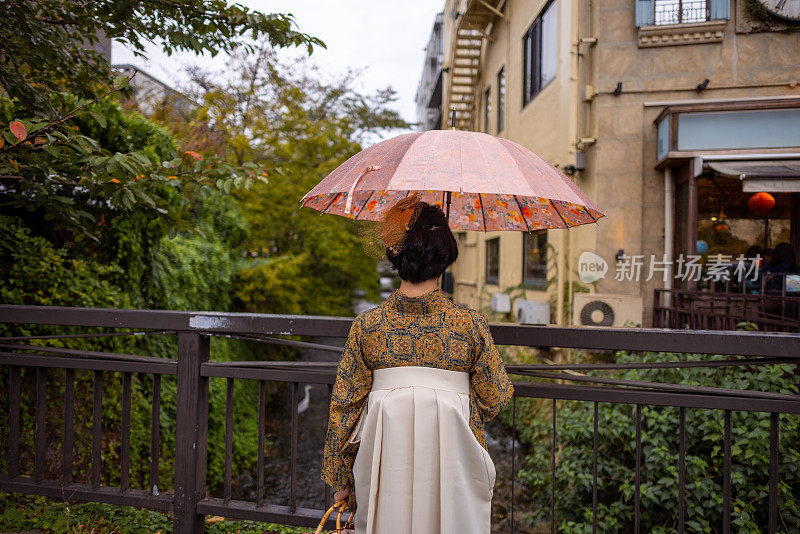 身穿和服的年轻女子站在桥上的后视图