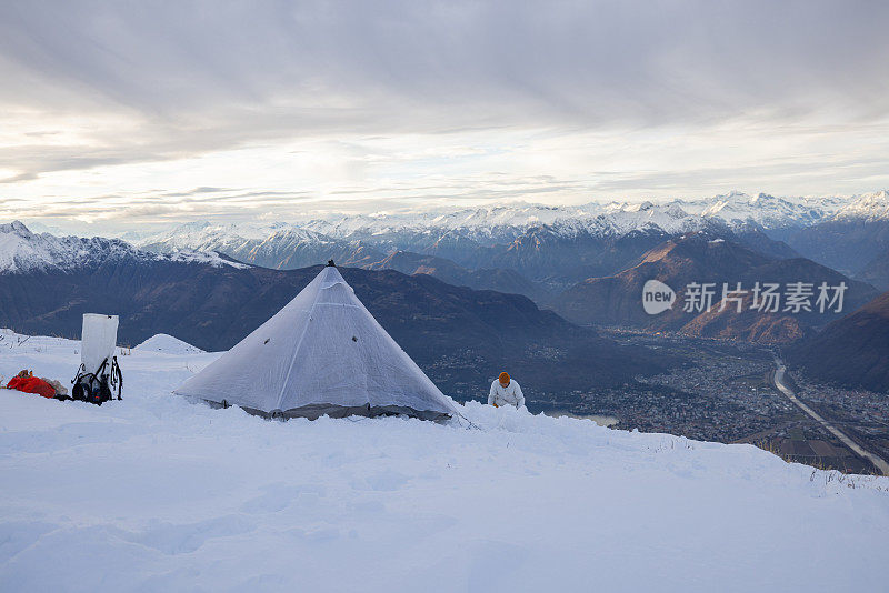 在雪地里露营，帐篷是建在一个湖、山脉之上的高峰上