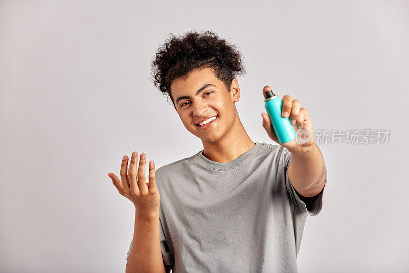 黑色卷发的年轻人将洗面奶涂在手上，准备开始他的日常美容和护肤程序。男士准备好好洗脸，为肌肤清新健康打下基础。