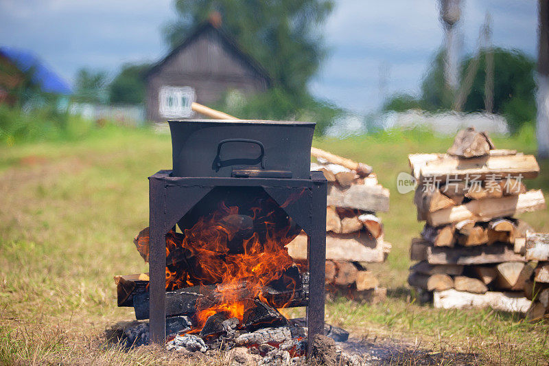 食物是在乡下的背景上用大锅在火上煮的。