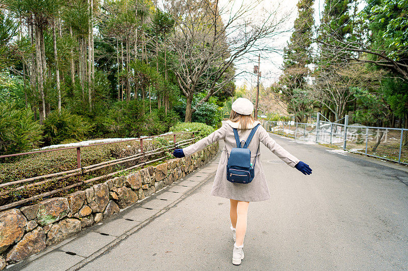 美丽的女游客漫步享受他们的竹林之旅在日本冬天