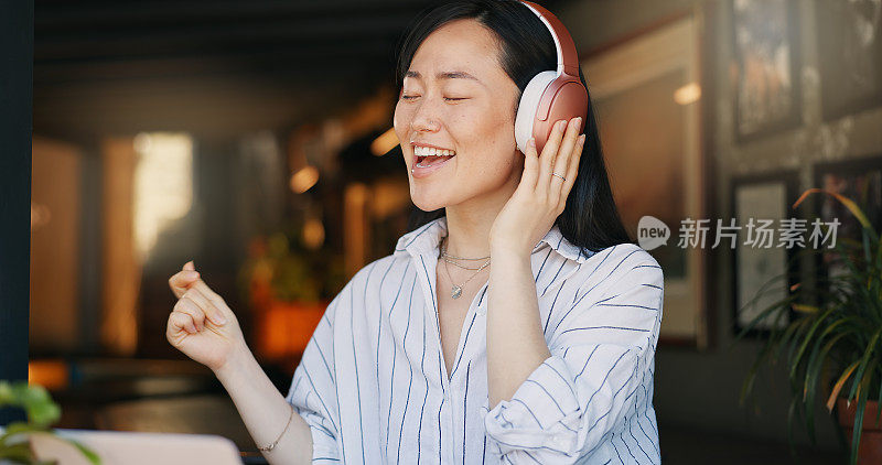 快乐的亚洲女人，耳机和听播放列表的音乐在咖啡馆的音频流媒体，跳舞或唱歌。女性或自由职业者在咖啡馆或餐厅微笑或享受播客，声音或歌曲