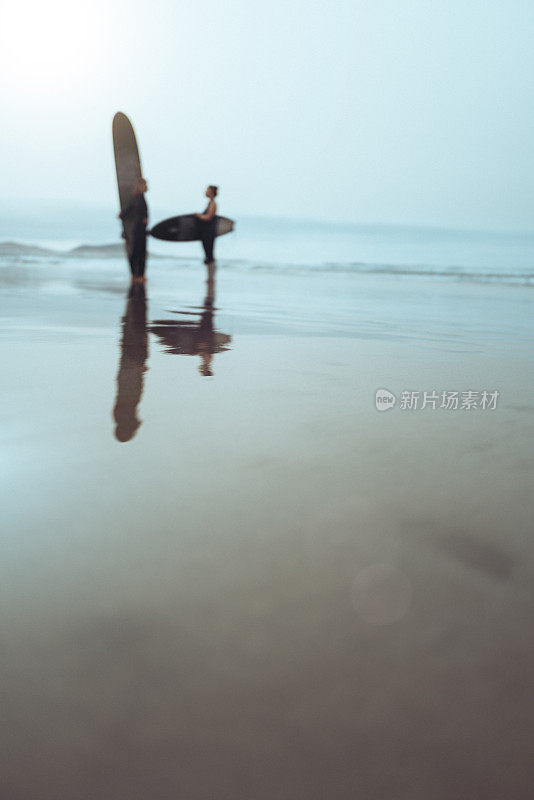 女冲浪手拿着冲浪板站在海岸线上