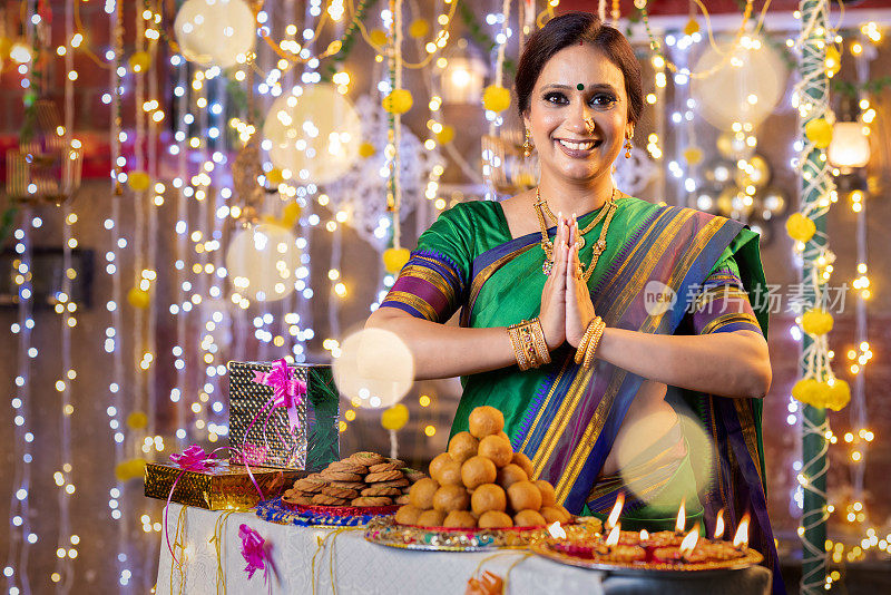 美丽的印度女人穿着纱丽在排灯节用合十手势问候。