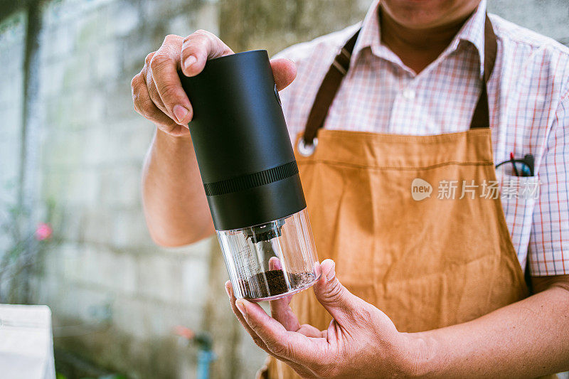 咖啡师在特写镜头中展示便携式咖啡研磨机，突出了必备的冲泡设备和咖啡豆