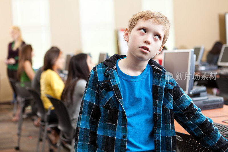 年轻的学生在学校的计算机实验室里感到无聊