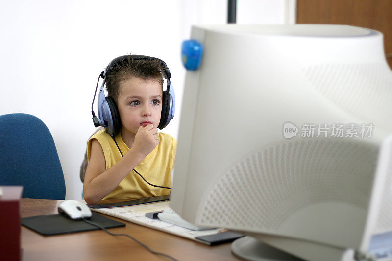 男孩戴着大耳机在电脑上玩游戏