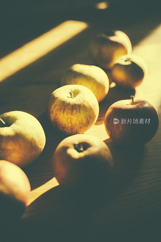 阳光下，木桌子上刚摘下来的苹果