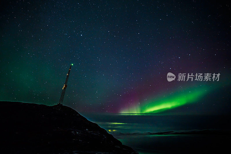山上的无线电发射塔和云层覆盖的北极光