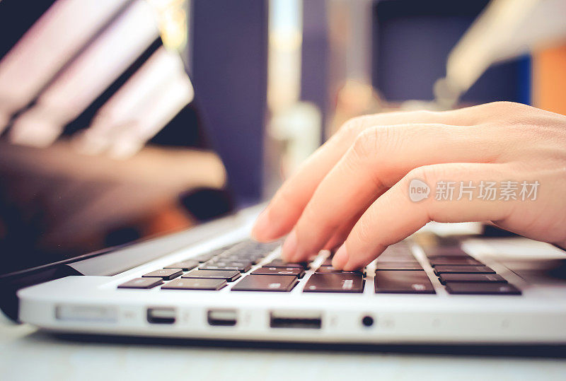 女性的手在笔记本电脑键盘上打字