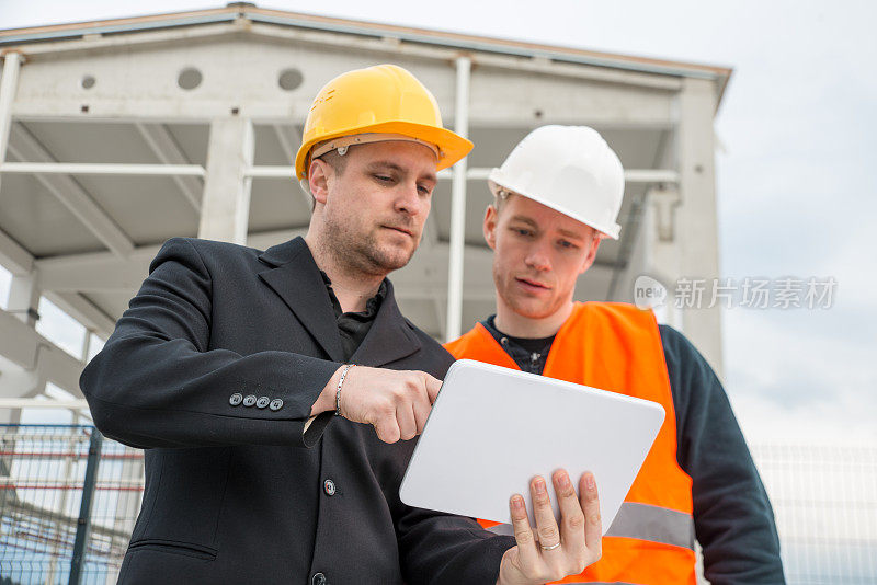 建筑师和建筑工人在平板电脑上看蓝图