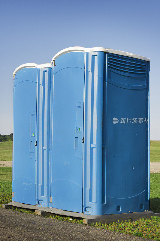 夏日晴空下的户外两个蓝色移动厕所