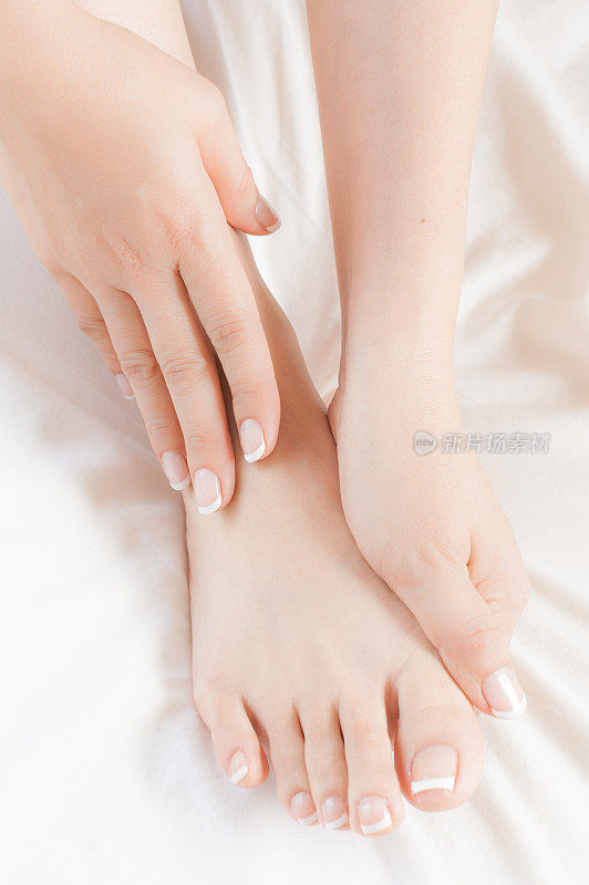 女人在白床单上按摩自己修脚的脚
