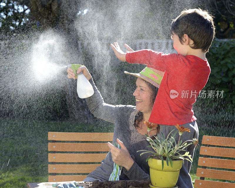 母亲和儿子在花园里玩喷雾器