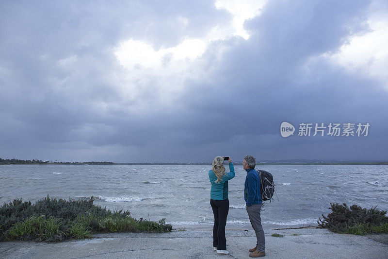 徒步情侣在水边驻足留影