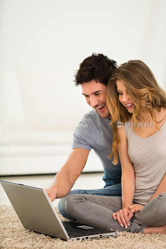 年轻夫妇在家用笔记本电脑工作