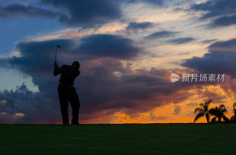 高级高尔夫球手在日落时开球的剪影
