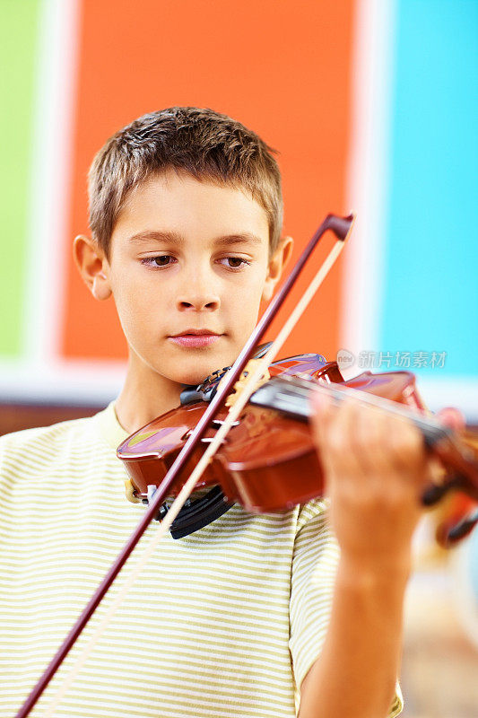 一个小男孩在教室里拉小提琴