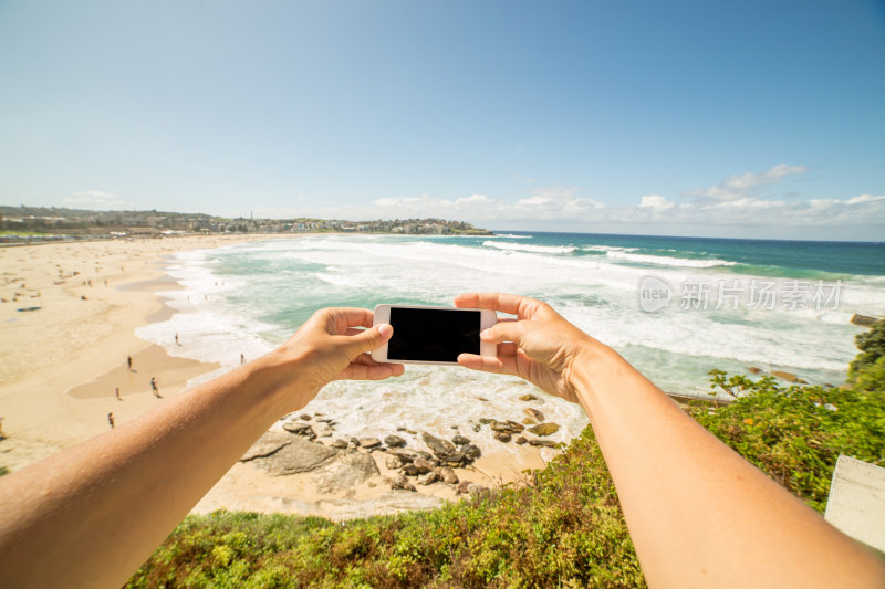 个人视角的女人拿着手机拍照的海滩