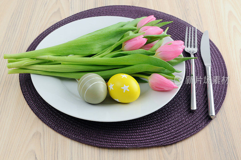 盘子里放了一束粉色郁金香和复活节彩蛋