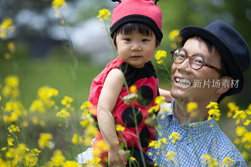 年轻的父亲和他可爱的女儿穿着瓢虫装