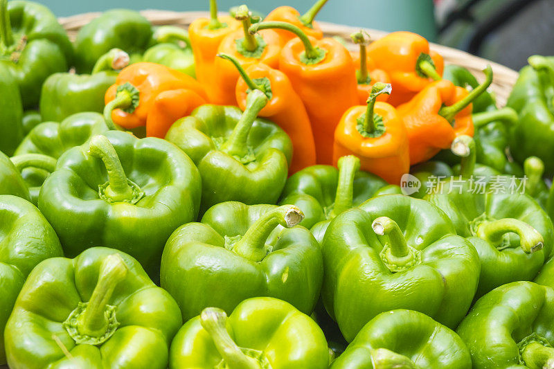 绿色和橙色灯笼椒堆在农贸市场