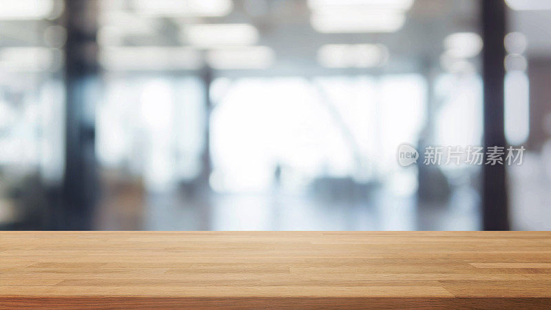 木质桌面和模糊的散景办公室室内空间背景-可以用来展示或蒙太奇您的产品。