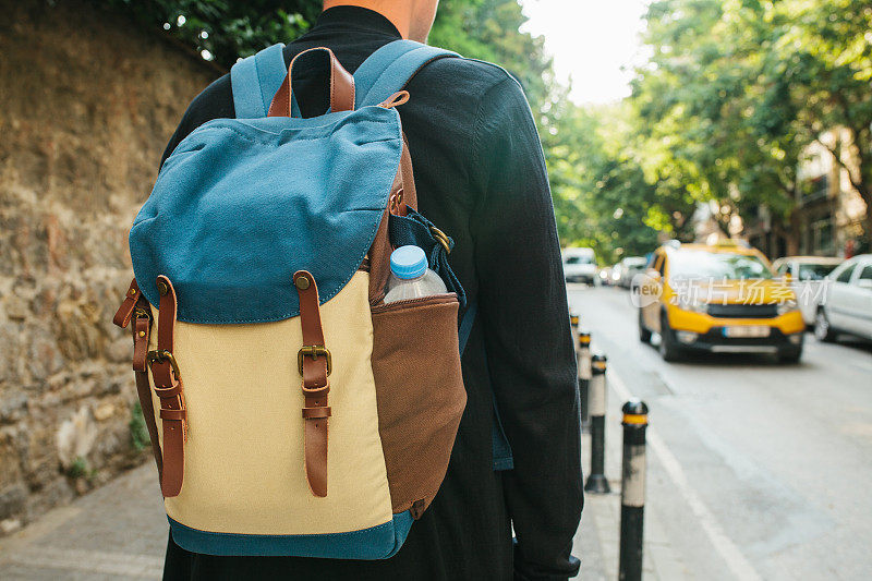一个背着背包的年轻男游客正在大城市里等出租车。的旅程。观光。旅行。