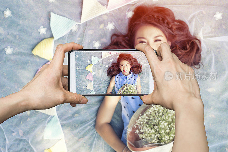 女孩正在用手机拍照，一个漂亮的年轻女孩拿着一束花