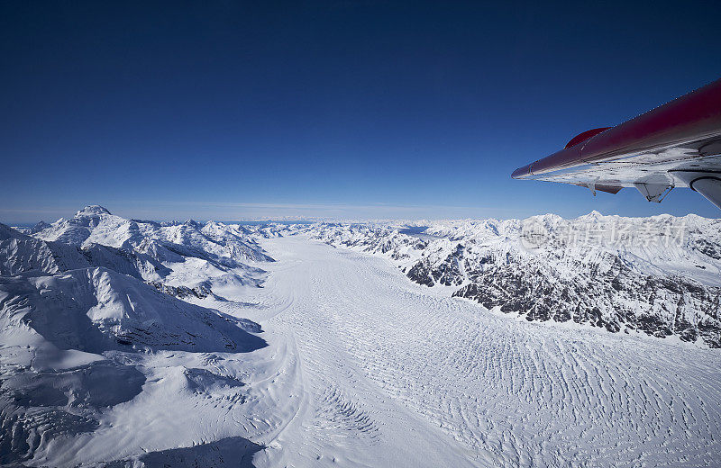 德纳里飞机窗外的冰川和山脉的航拍照片。