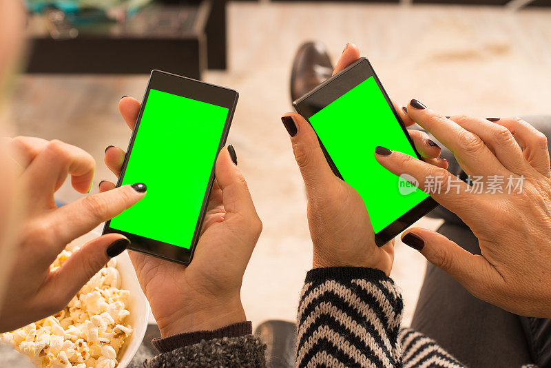 两个成年女性使用带绿屏的智能手机