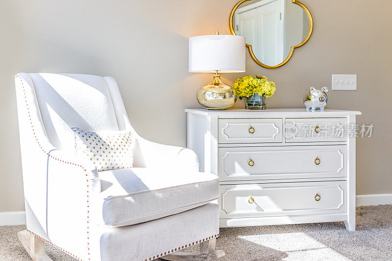 明亮的白色现代摇椅在婴儿室与抽屉柜，装饰在模型分期家，公寓或房子