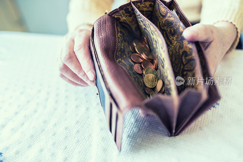 退休妇女手里拿着装有欧元硬币的钱包