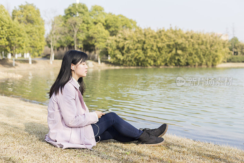 一个春天的下午，年轻女子戴着耳机在草坪上放松