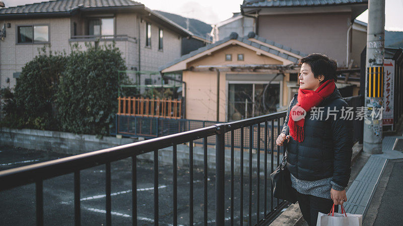 在京都街头，一名戴着红领巾的亚裔华人女子望向远方