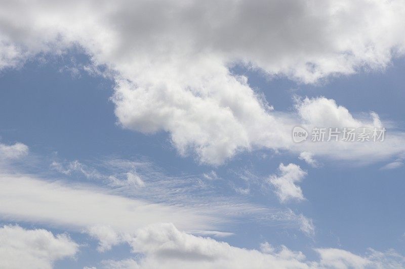 蓝色天空映衬着蓬松、缕缕白云的特写