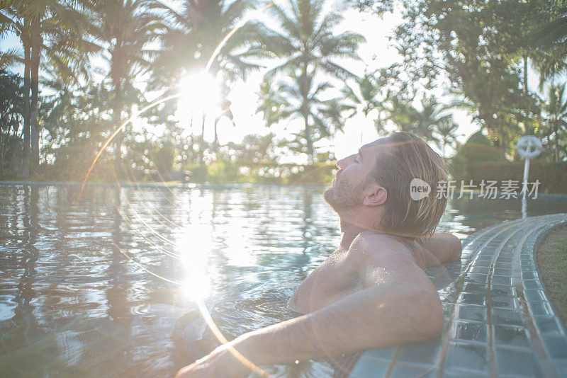 在度假村温泉的热水浴缸健康在热带天堂-男人放松在豪华度假村温泉撤退室外的热水浴缸池。快乐的年轻男模特放松休息在水上度假旅游。