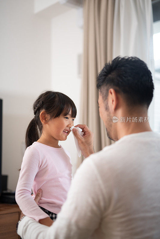 父亲在家里给女儿擦鼻子