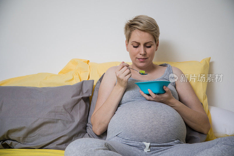 快乐的孕妇在家吃蔬菜沙拉当早餐