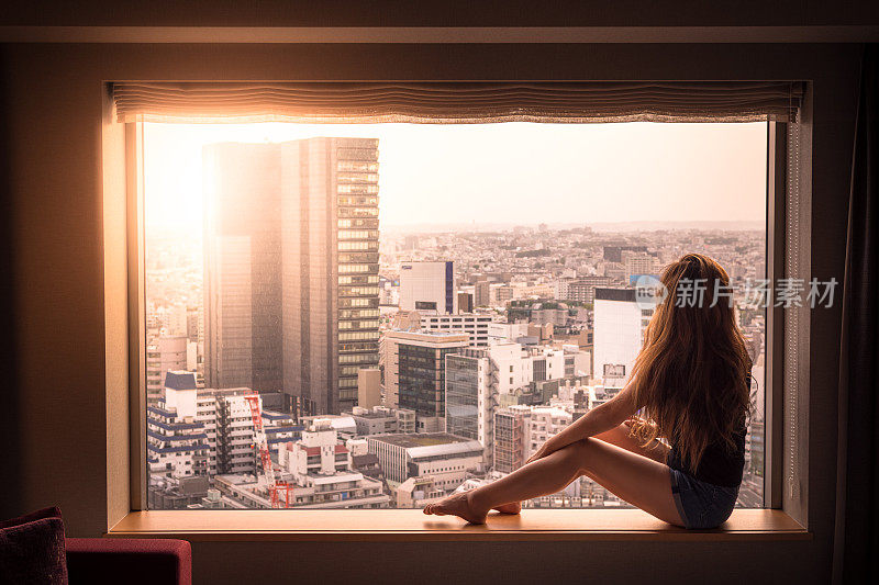 在日本东京涩谷，一名女子看着窗外的酒店