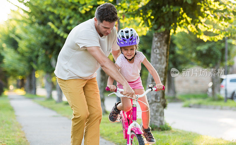 快乐的父亲教他的小女儿骑自行车
