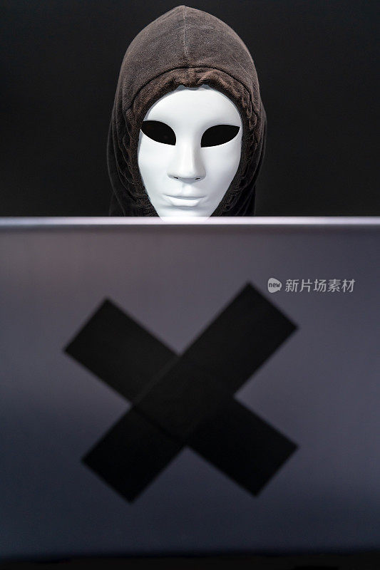 戴着面罩的电脑黑客用笔记本电脑窃取信息